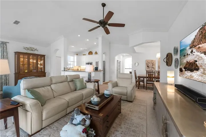 Spacious living room with ceiling fan and seamless flow to kitchen and dining.