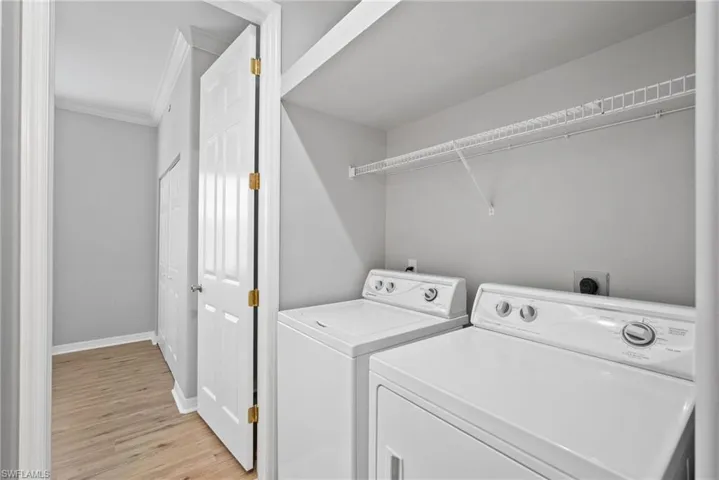 Laundry area with light wood-type flooring, independent washer and dryer, and ornamental molding