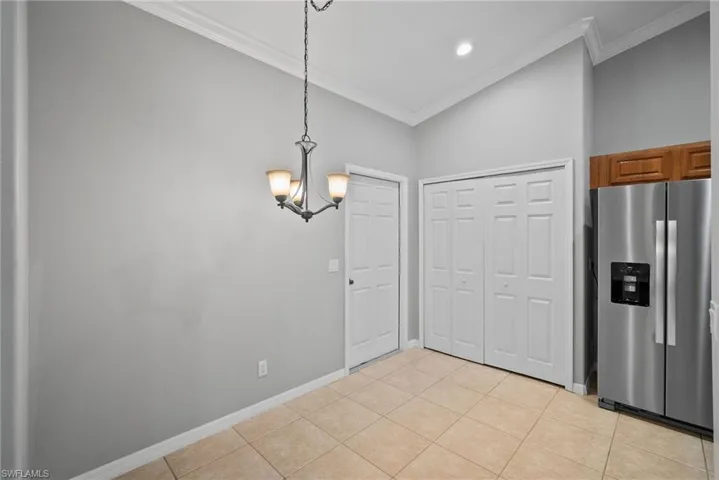 Kitchen with ornamental molding, light tile patterned flooring, and stainless steel refrigerator with ice dispenser