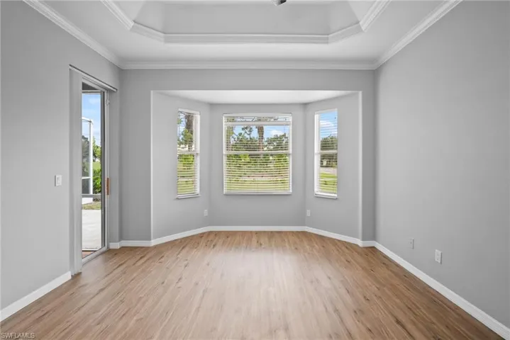 Empty room with hardwood / wood-style flooring, a raised ceiling, and crown molding