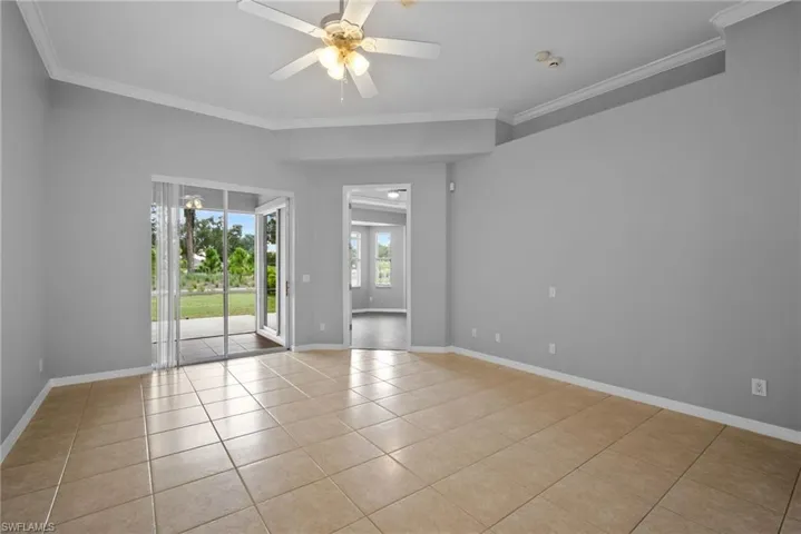 Tiled spare room with ceiling fan and crown molding
