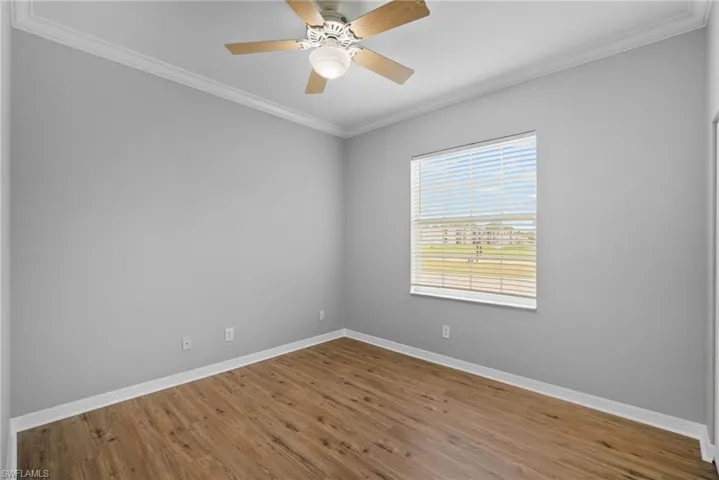 Spare room featuring ceiling fan, crown molding, and wood-type flooring