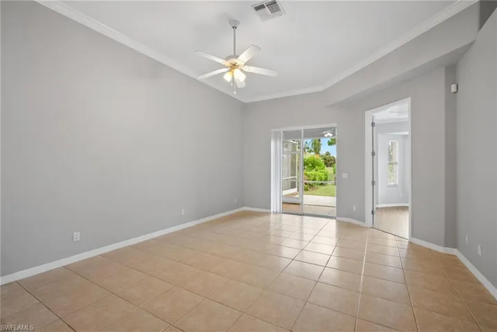 Tiled spare room with ceiling fan and crown molding