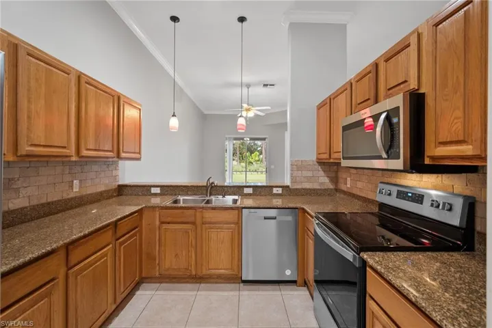 Kitchen featuring ceiling fan, pendant lighting, appliances with stainless steel finishes, sink, and kitchen peninsula