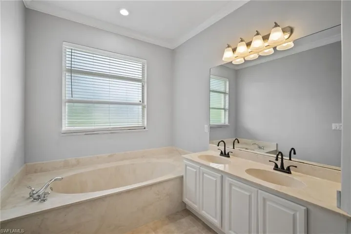 Bathroom with a wealth of natural light, a bathtub, dual bowl vanity, and tile patterned flooring