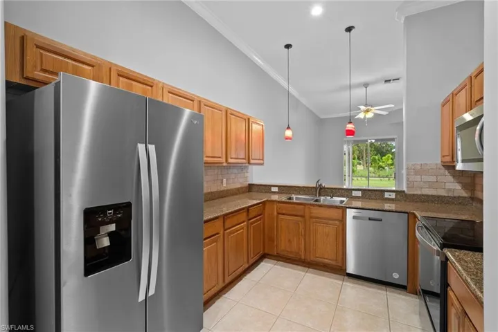Kitchen with appliances with stainless steel finishes, ceiling fan, kitchen peninsula, and tasteful backsplash