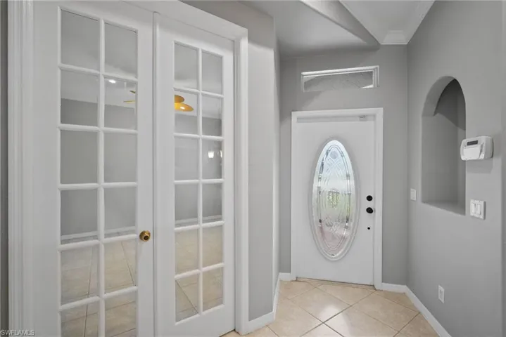 Doorway with ornamental molding and light tile patterned floors