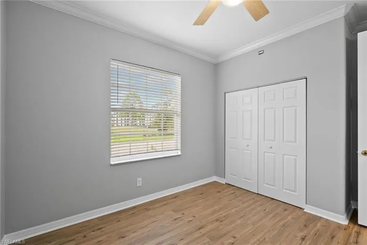 Unfurnished bedroom featuring ceiling fan, a closet, light hardwood / wood-style floors, and ornamental molding