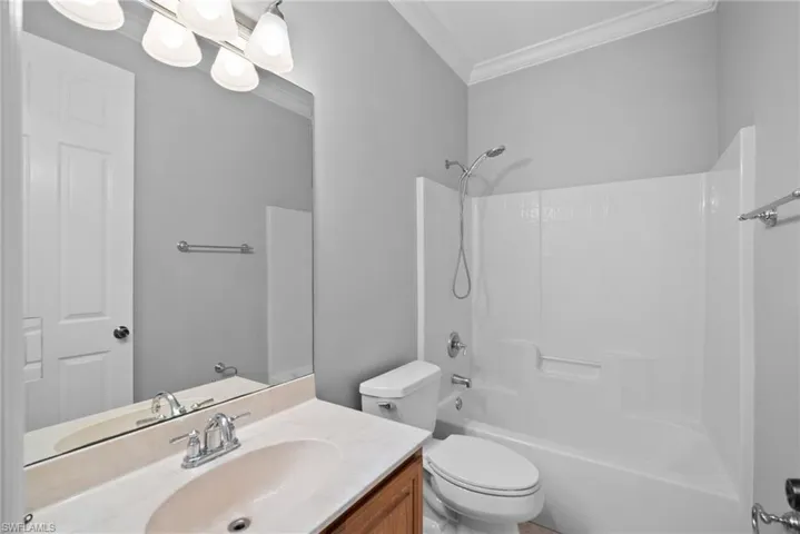 Full bathroom featuring toilet, crown molding, bathtub / shower combination, and vanity