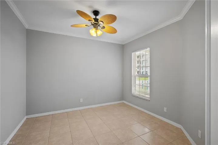 Spare room featuring ceiling fan, light tile patterned floors, and crown molding