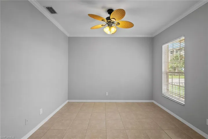 Spare room with ceiling fan, plenty of natural light, light tile patterned flooring, and ornamental molding