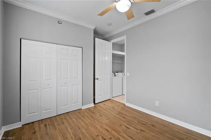 Unfurnished bedroom with ornamental molding, light wood-type flooring, independent washer and dryer, a closet, and ceiling fan