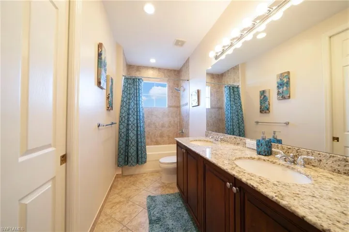 Bathroom featuring shower / tub combo, double vanity, light tile patterned flooring, and recessed lighting