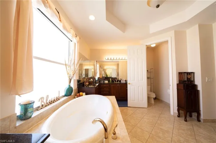 Full bathroom with vanity, a garden tub, light tile patterned floors, and recessed lighting