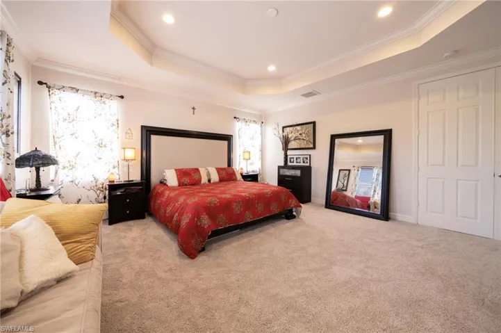 Bedroom featuring a raised ceiling, crown molding, light colored carpet, and recessed lighting