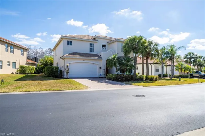 Mediterranean / spanish house featuring a front yard, a garage, driveway, stucco siding, and a tile roof
