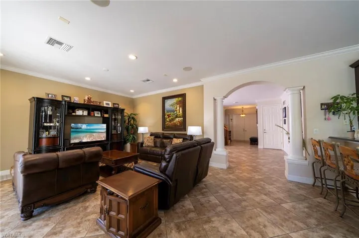 Den featuring crown molding, decorative columns, and recessed lighting