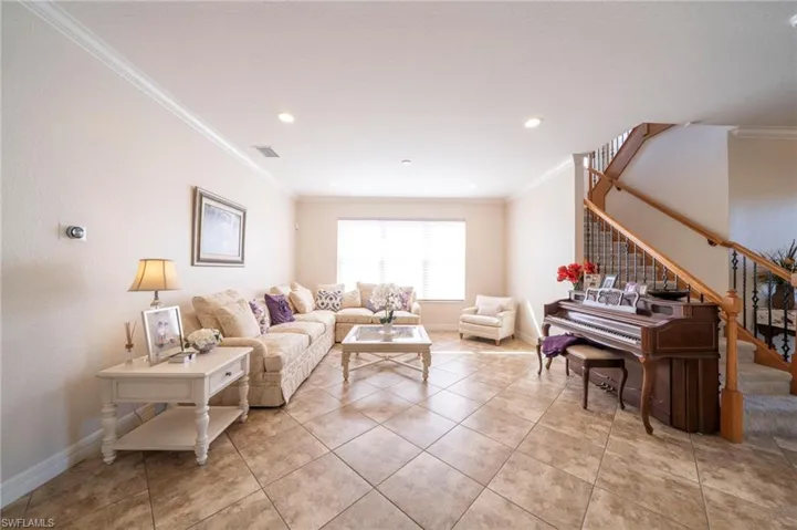 Living area with crown molding, recessed lighting, and light tile patterned flooring