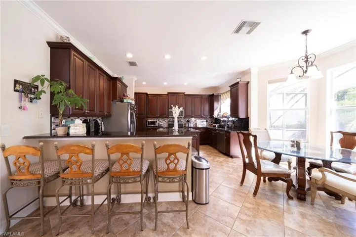 Kitchen with dark wood finish cabinets, a breakfast bar area, a peninsula, crown molding, and stainless steel appliances
