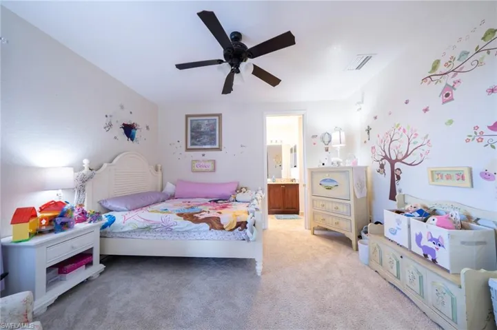 Bedroom with light colored carpet, ensuite bath, and a ceiling fan