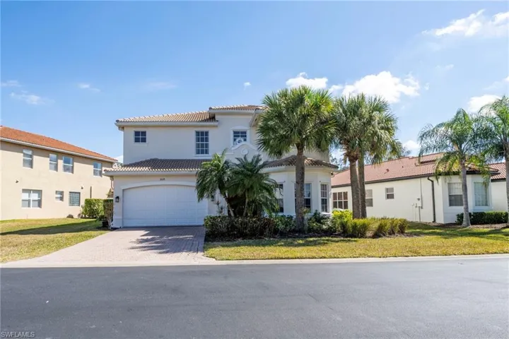 Mediterranean / spanish house with a tile roof, driveway, an attached garage, a front lawn, and stucco siding