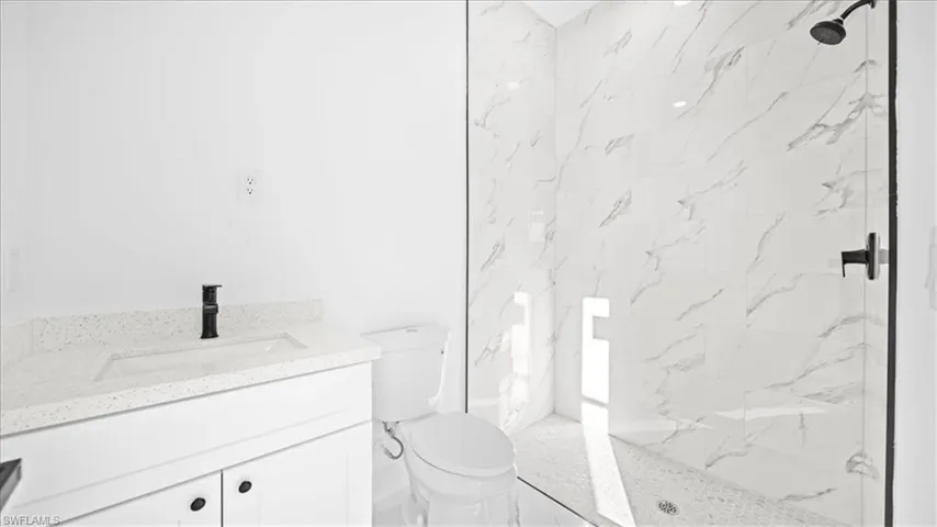 Full bathroom featuring vanity and a marble finish shower
