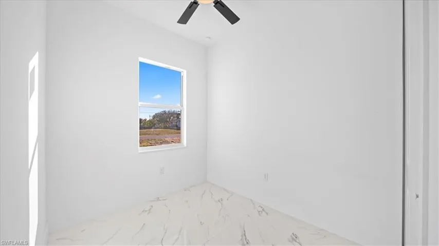 Spare room featuring light marble finish floors and a ceiling fan