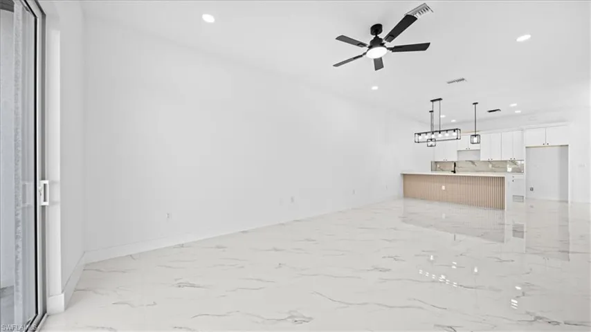 Unfurnished living room featuring recessed lighting, light marble finish flooring, and ceiling fan