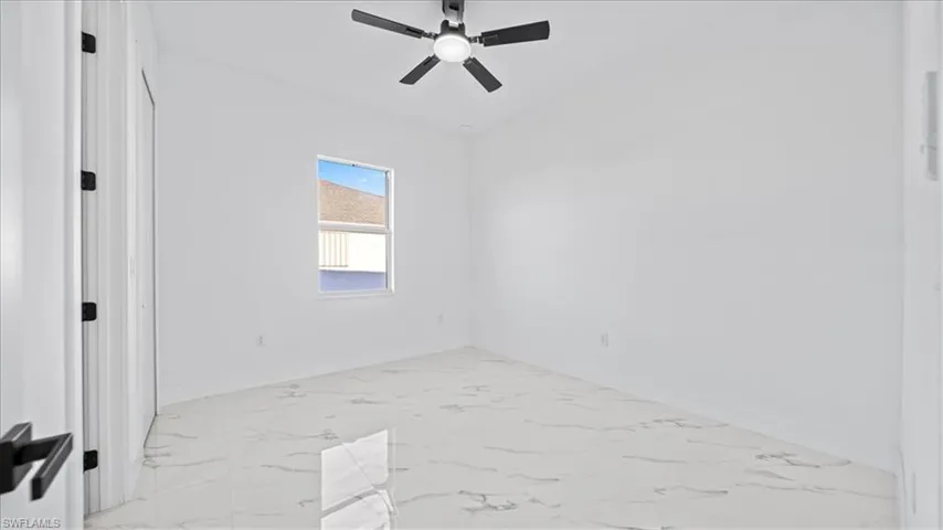 Spare room with light marble finish floors and ceiling fan
