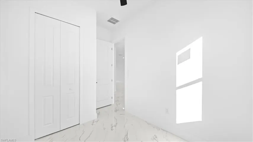 Unfurnished bedroom featuring a ceiling fan, a closet, and light marble finish flooring