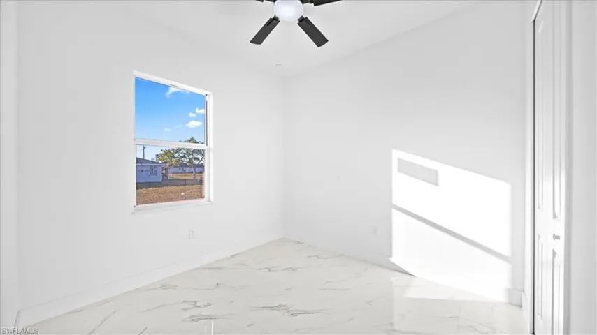 Spare room with light marble finish flooring and ceiling fan