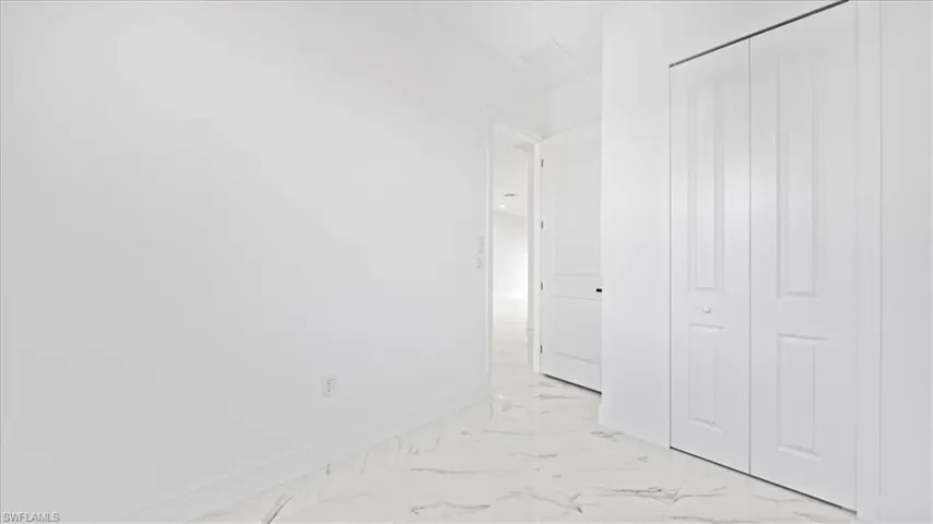 Unfurnished bedroom with light marble finish flooring and a closet