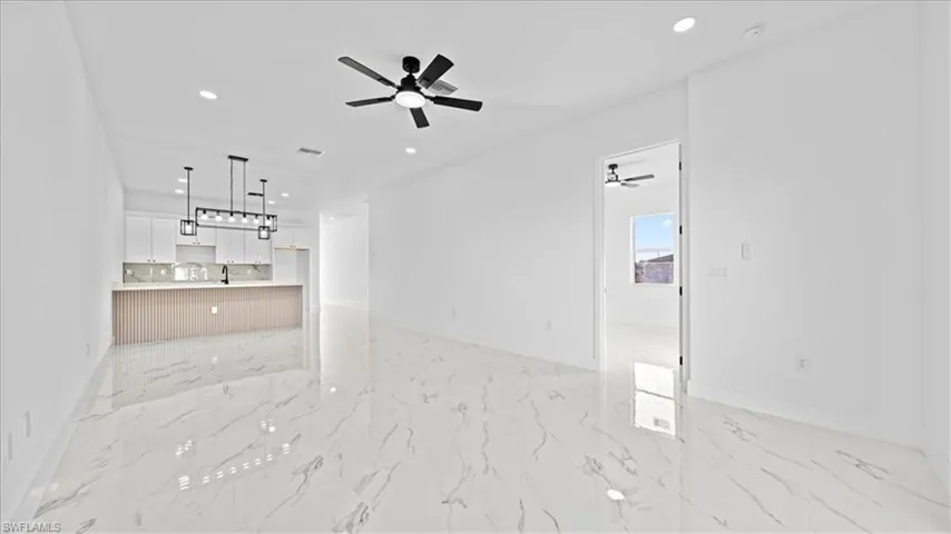 Unfurnished living room featuring recessed lighting, light marble finish floors, and a ceiling fan