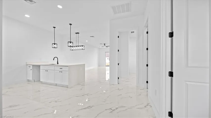 Kitchen featuring a peninsula, white cabinets, recessed lighting, pendant lighting, and open floor plan