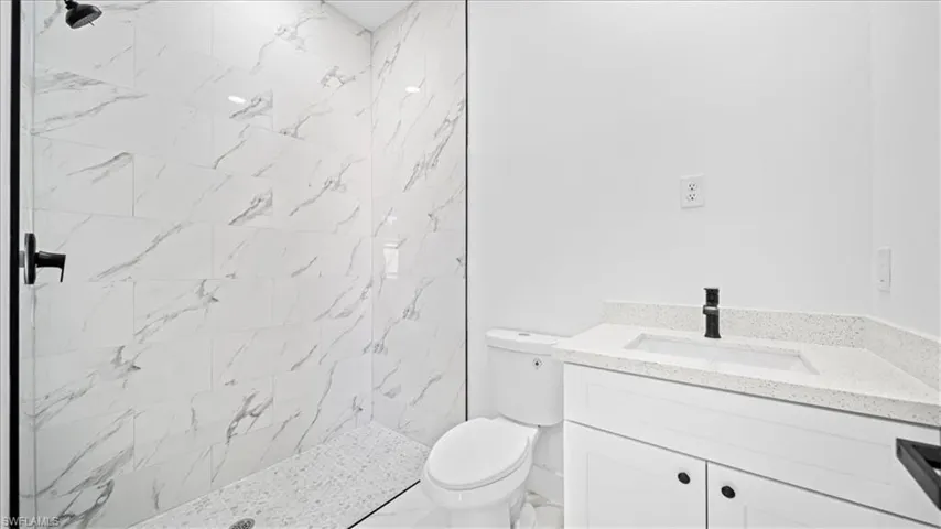 Full bath with a marble finish shower and vanity