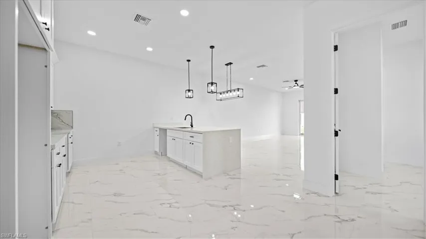 Kitchen featuring a peninsula, white cabinets, recessed lighting, light stone counters, and pendant lighting