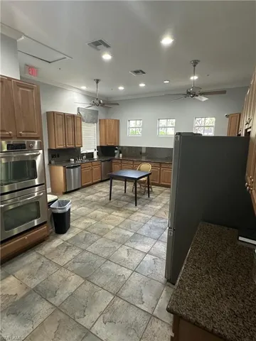 Kitchen with appliances with stainless steel finishes, sink, ceiling fan, and light tile floors