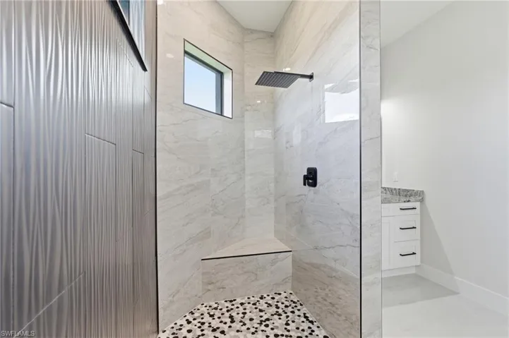 Primary walk-in shower featuring tiled shower and two vanities