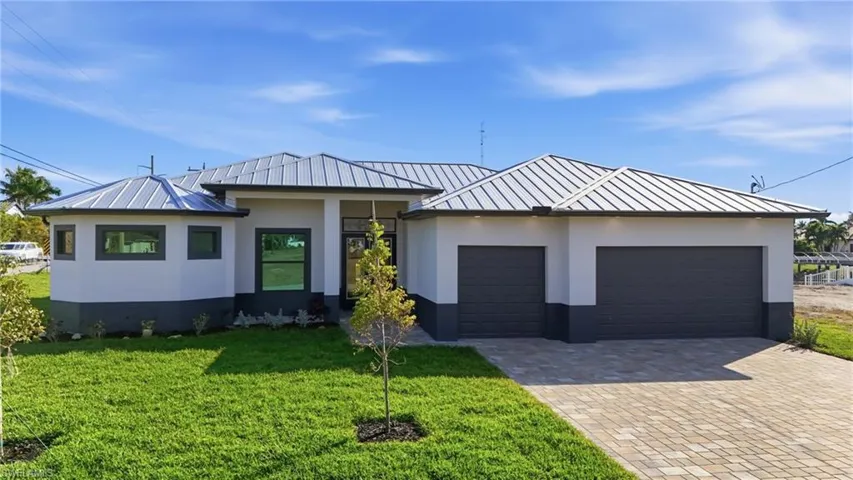 View of front of home with a standing seam roof, an attached garage, and stucco siding