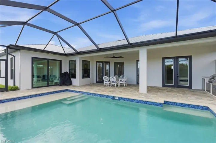 Back of home with stucco siding, ceiling fan, a metal roof, and a screened lanai