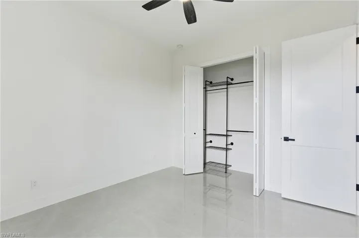 Guest bedroom featuring a closet, ceiling fan, and light tile flooring
