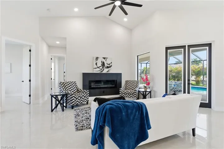 Living room with a electric fireplace, a ceiling fan, vaulted ceiling, and recessed lighting