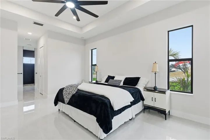 Primary bedroom featuring a ceiling fan, a raised ceiling, and recessed lighting