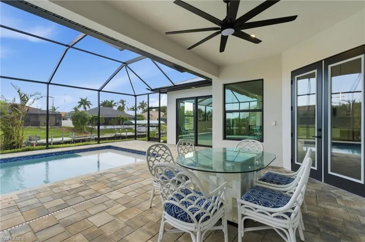View of patio featuring outdoor dining space, an outdoor pool, ceiling fan, and a lanai