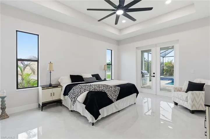 Primary bedroom with French doors to screened lanai, tray ceiling,  ceiling fan, and recessed lighting