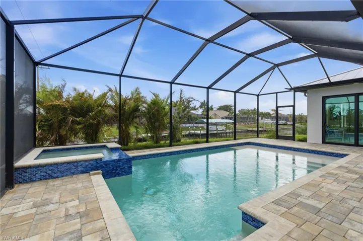 Relaxing pool / spa featuring a screened lanai, and pavers