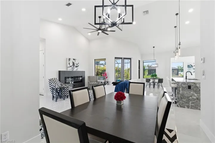 Dining room featuring a chandelier, ceiling fan, vaulted ceiling, and light tile floors