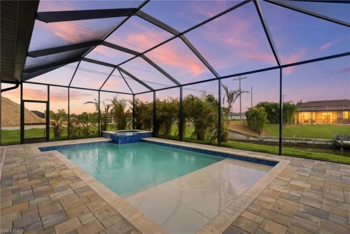 Pool at dusk featuring a pool with connected hot tub