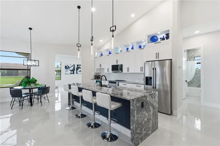 Kitchen with stainless steel appliances, plenty of natural light, vaulted ceiling, decorative light fixtures, and premium counters