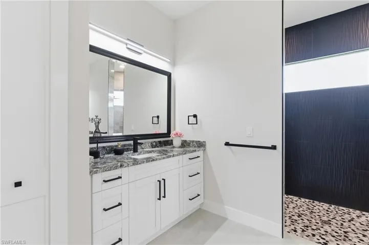primary bathroom with two vanities, walk in shower, and ample amount of natural light